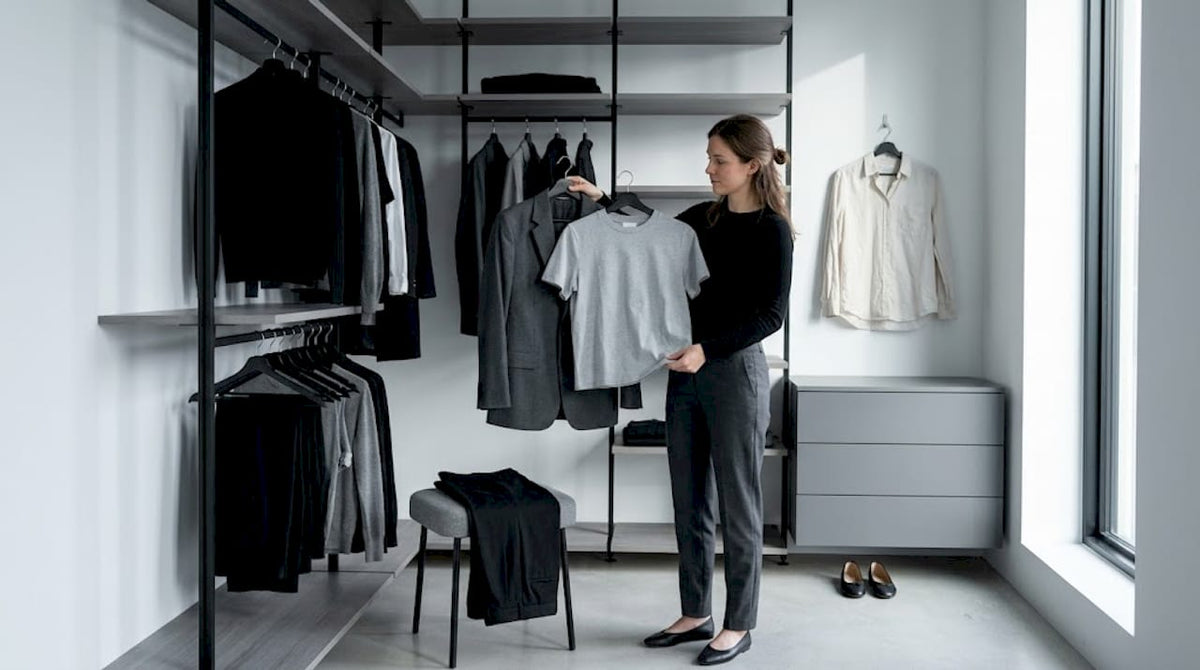 Eine Frau stellt vor ihrem offenen Kleiderschrank verschiedene Outfits zusammen.